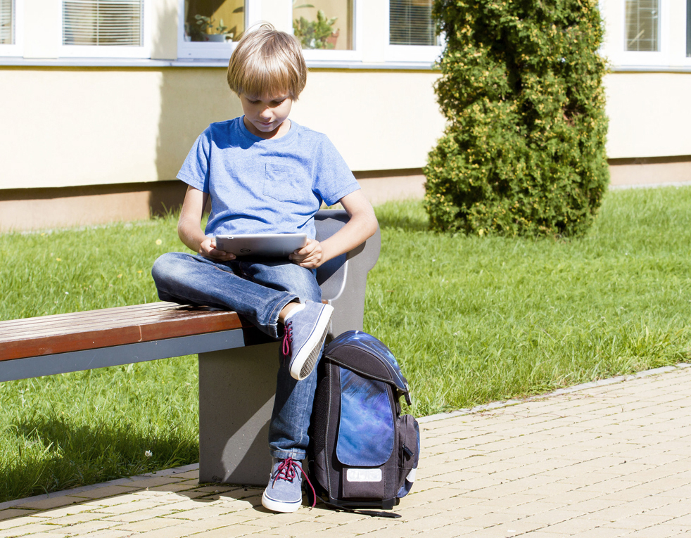 61689745 - schoolboy with tablet pc sitting on the bench near school. outdoor. education, technology people concept